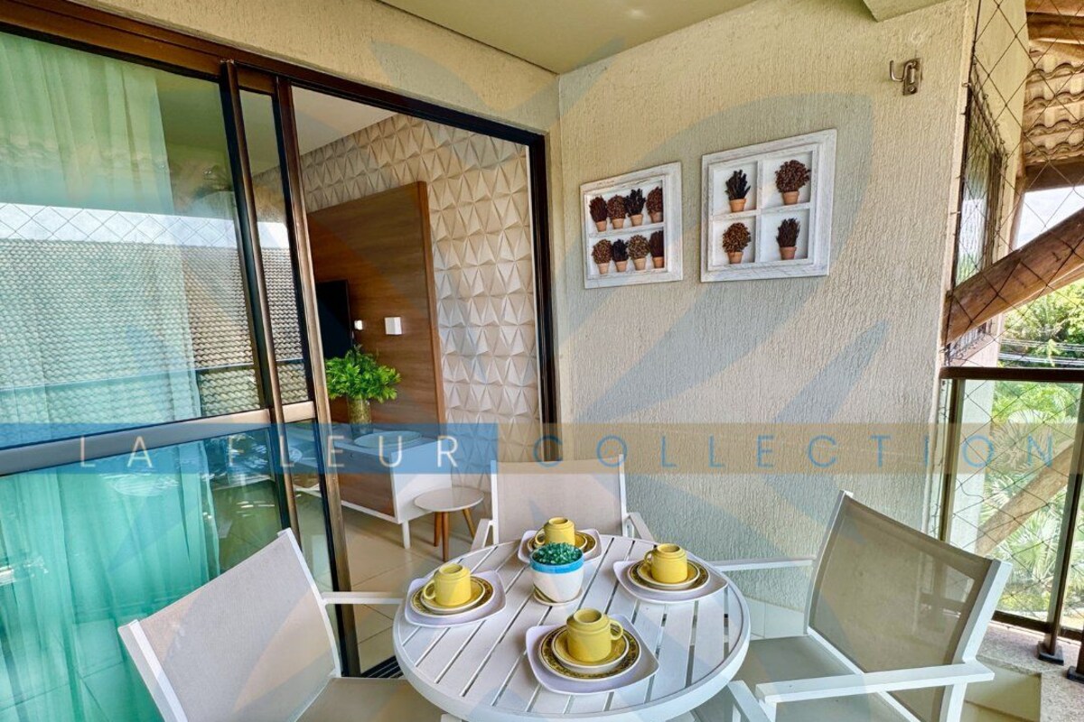 A balcony with a round table and chairs, a glass door, and a view of the outside.