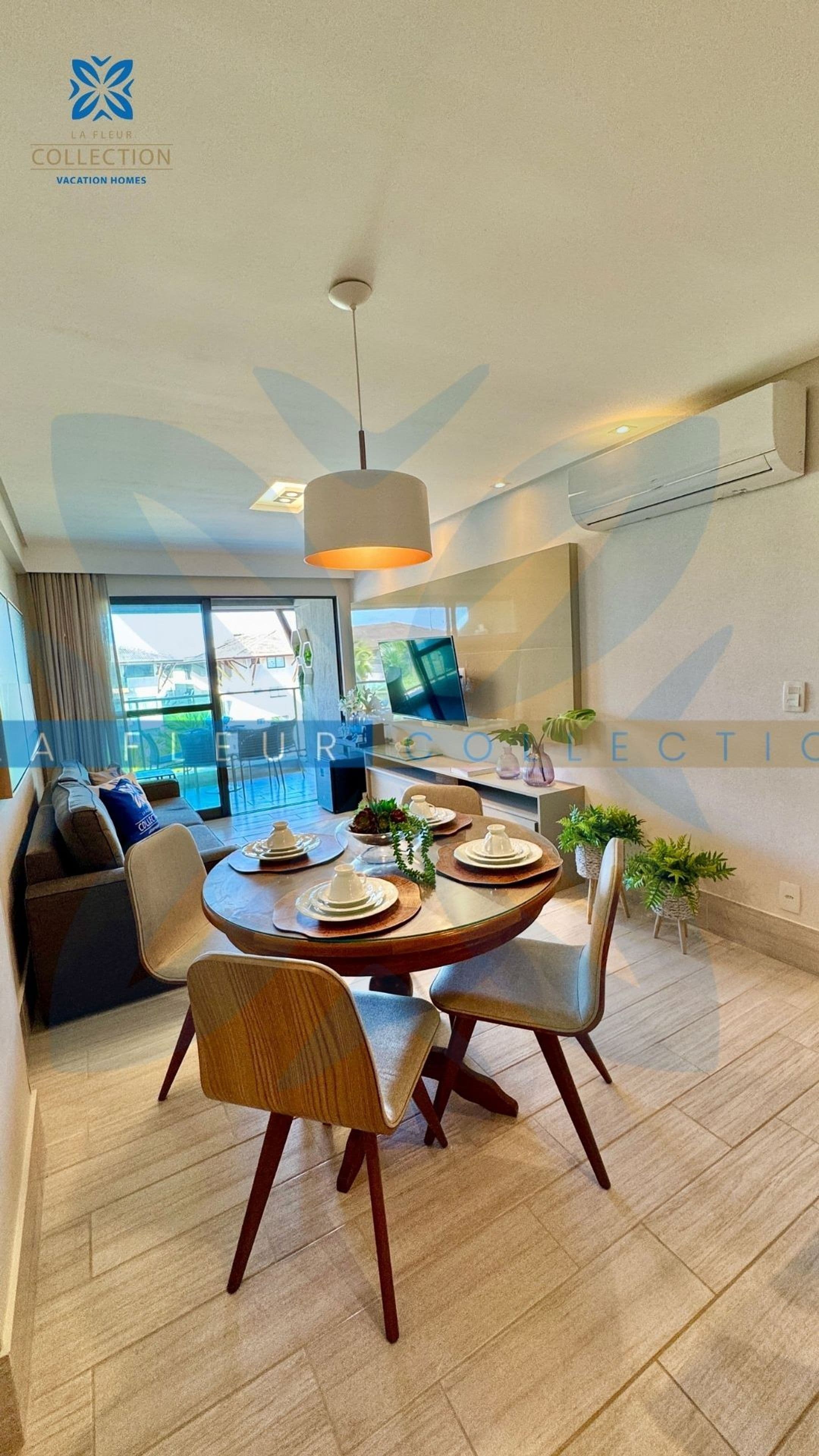 Uma área de jantar moderna com mesa redonda, cadeiras e um lustre.