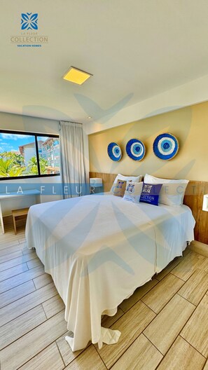 A hotel room with a large bed, a desk, and a view of palm trees. - La Fleur Collection Vacation Homes (Ipojuca)