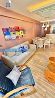 Un salon moderne avec un canapé, une table à manger et des chaises, ainsi que des œuvres d’art abstraites et colorées accrochées au mur.
