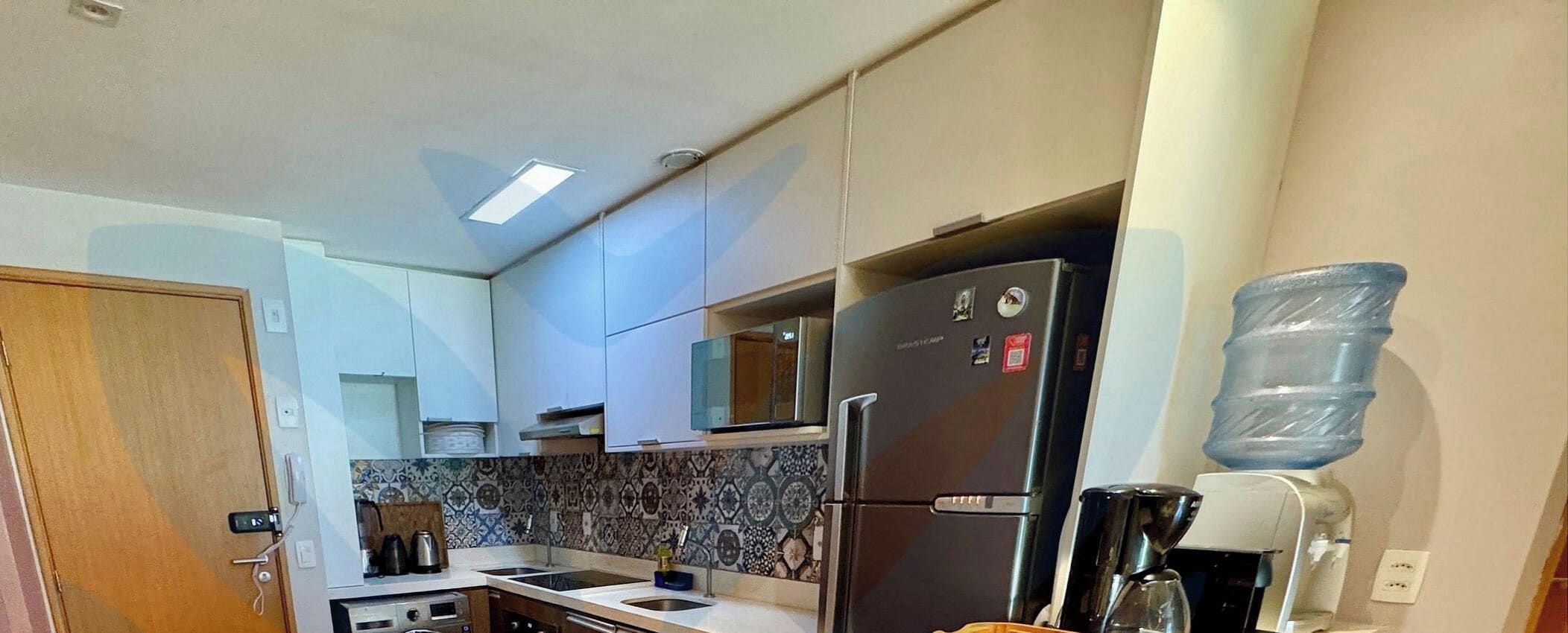 A compact kitchen with a refrigerator, sink, and a water dispenser.