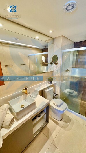 Une salle de bain moderne avec une douche à parois de verre, un meuble-lavabo avec un évier et un miroir, et des toilettes.