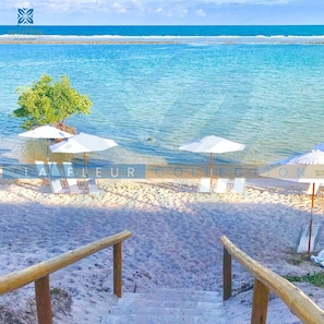 على الشاطئ، رمال بيضاء، كراسي للتشمس، مظلات الشاطئ