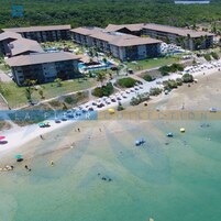 An aerial view of a resort with multiple buildings, a beach, and clear waters.