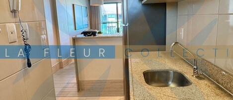 A modern kitchen with a built-in dishwasher, a stainless steel sink, and a window overlooking a balcony.