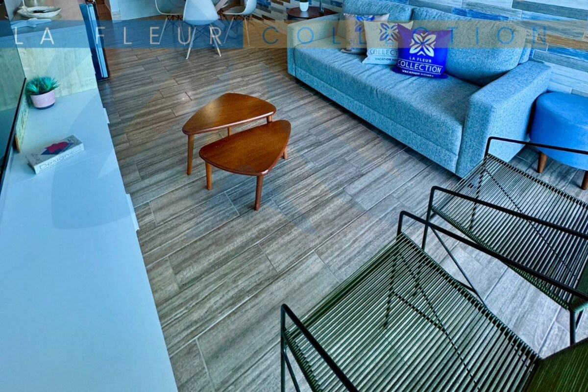 A modern living room with a blue sofa, wooden coffee table, and a patterned wall.