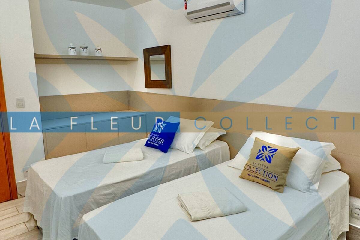 A hotel room with two beds, a mirror, an air conditioning unit, and a wooden floor.