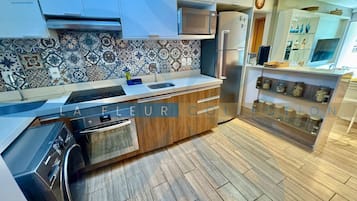 A modern kitchen with a patterned backsplash, stainless steel appliances, and wooden cabinetry.