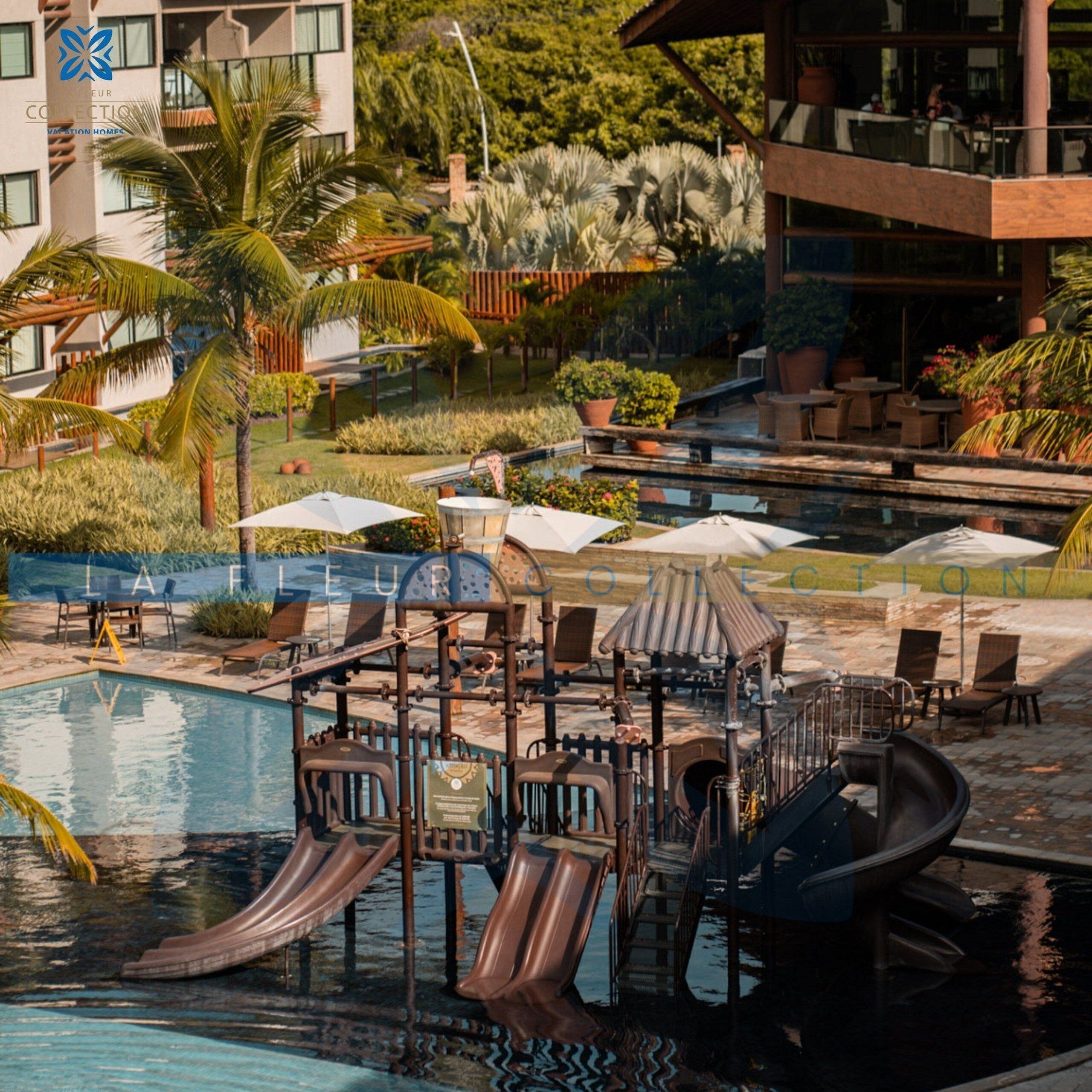 Área de piscina com toboáguas, espreguiçadeiras e guarda-sóis.