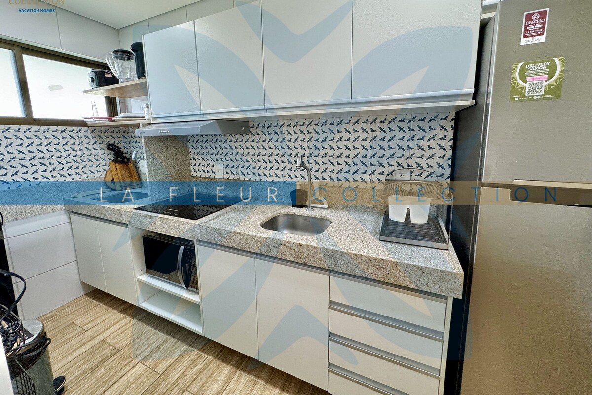 A modern kitchen with white cabinets, a stainless steel refrigerator, and a patterned backsplash.