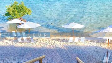 Am Strand, weißer Sandstrand, Liegestühle, Sonnenschirme