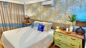A bedroom with a bed, a nightstand, a lamp, and a wall air conditioner. - La Fleur Collection Vacation Homes (Ipojuca)