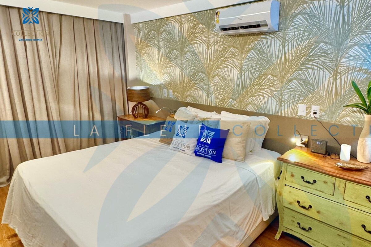 A bedroom with a bed, a nightstand, a lamp, and a wall air conditioner.