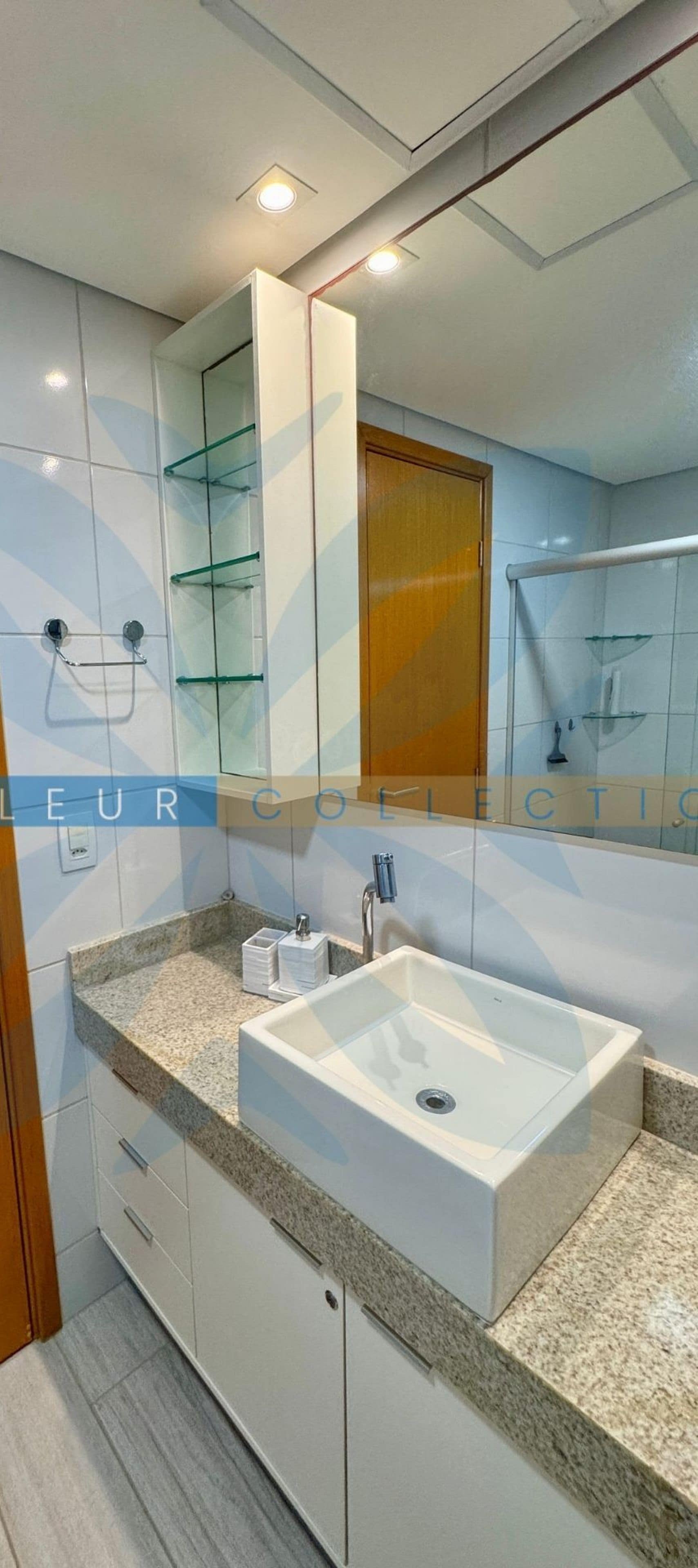 A modern bathroom with a large mirror, a white sink, and a granite countertop.