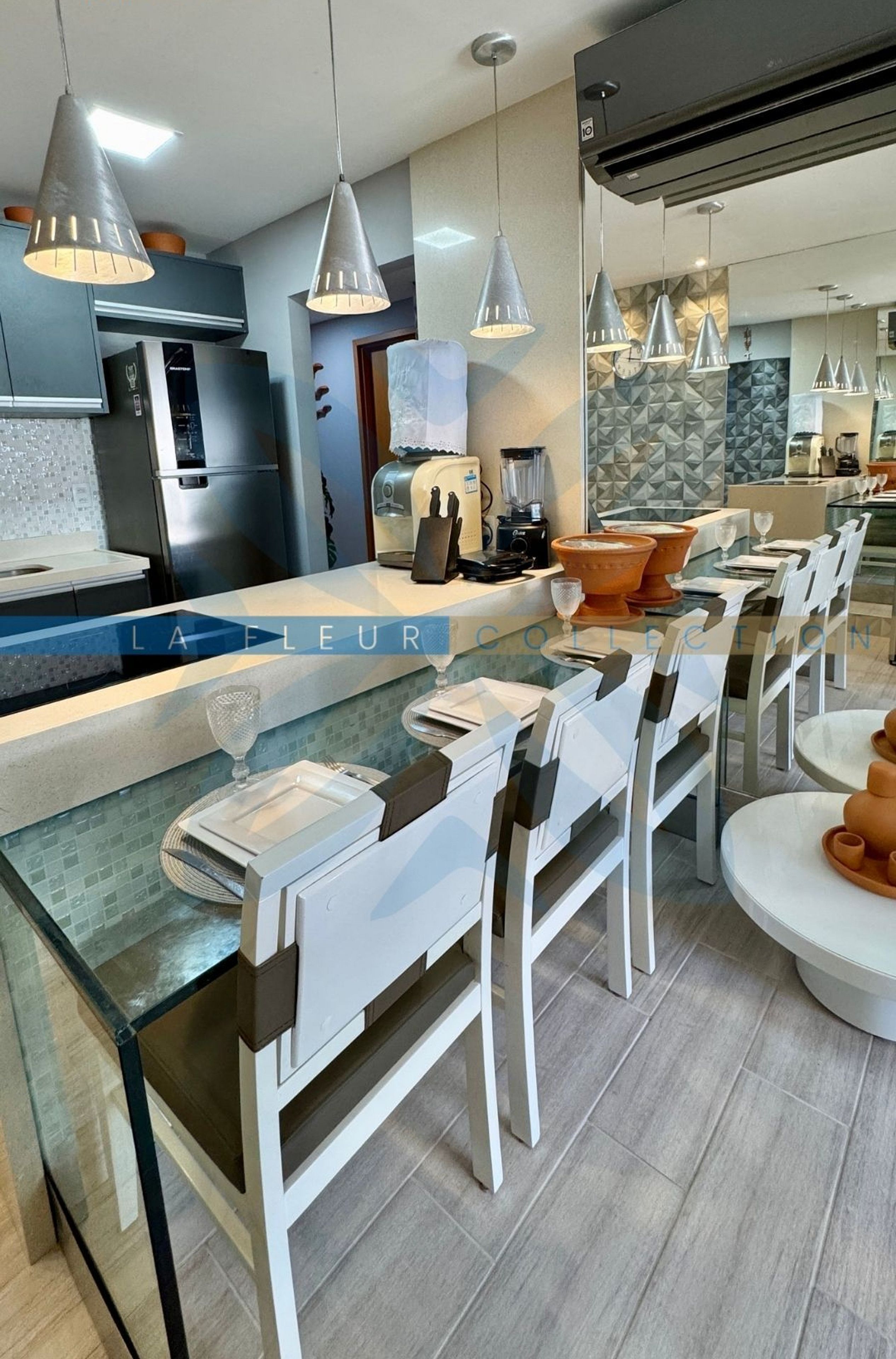 A modern kitchen with a central island, pendant lighting, and a dining area with chairs and tables.
