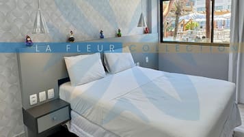 A modern bedroom with a bed, bedside tables, and a window with a view.