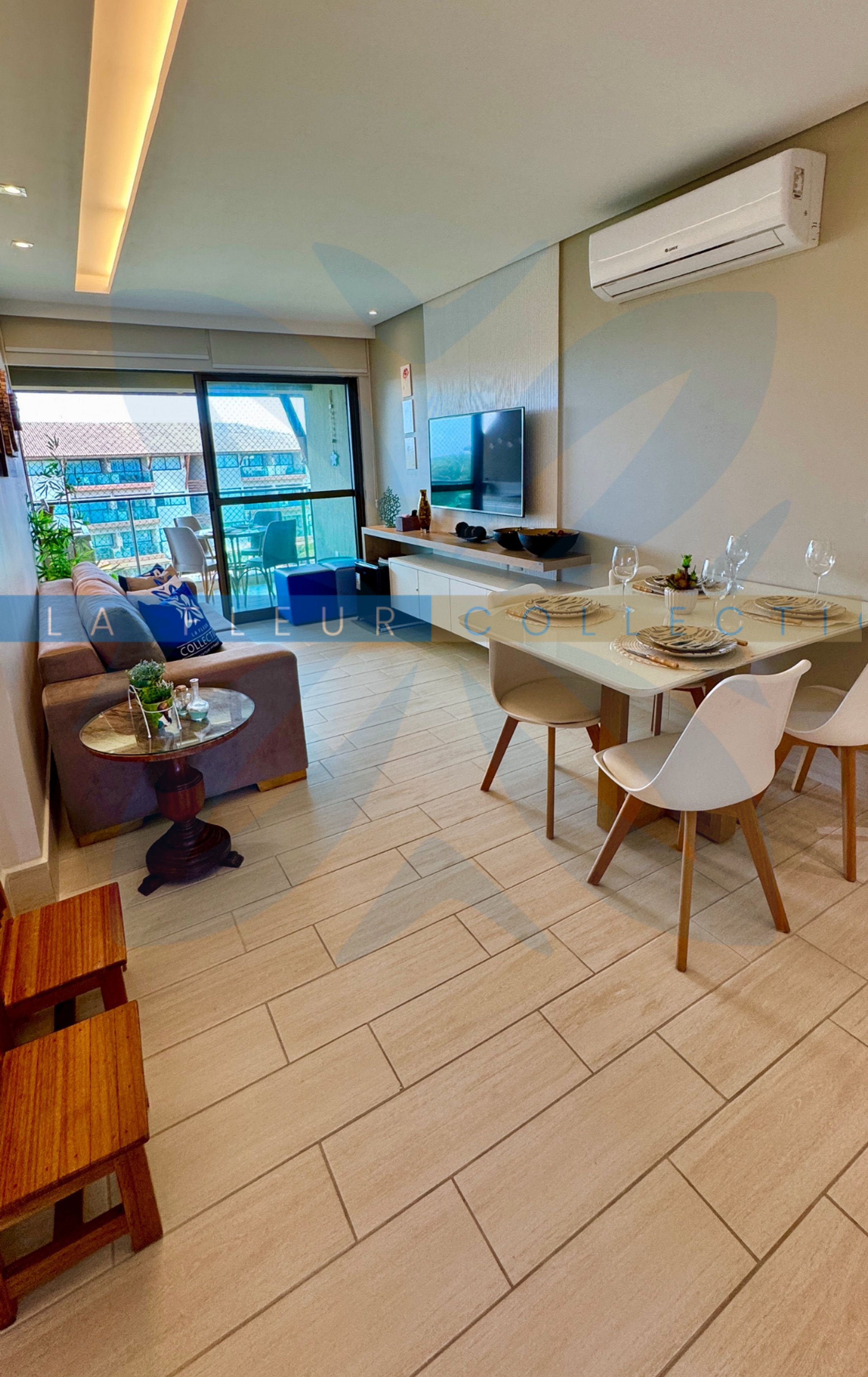A modern living room with a sofa, a dining table set for four, and a TV mounted on the wall.