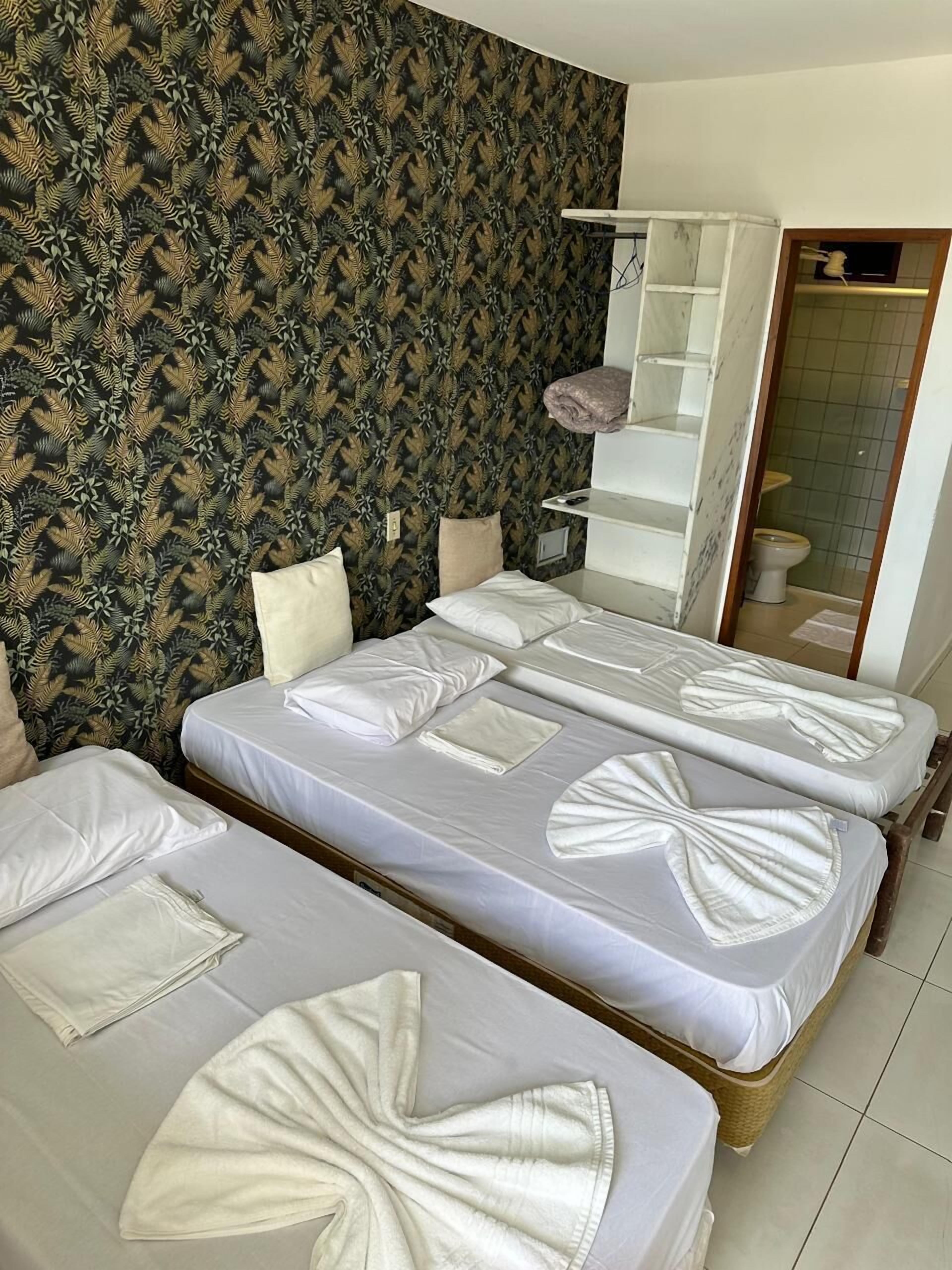 A hotel room with two beds, a bathroom with a shower, and a toilet.