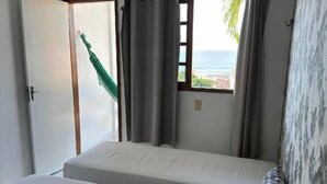 A bedroom with a bed, pillows, a hammock, and a view of the sea. - Pousada Praiana Pipa (Tibau do Sul)