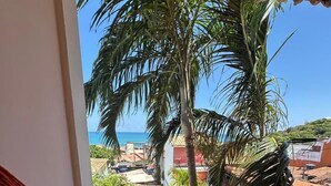 A hammock on a balcony with a view of the sea and palm trees. - Pousada Praiana Pipa (Tibau do Sul)
