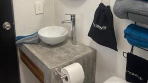A bathroom with a sink, mirror, towel rack, and toilet. - Spanish Moon PV - # 9 Queen Room, refrig. , micro.,coffee maker, pool, WiFi, TV (Puerto Vallarta)