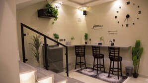 A modern kitchen with a bar area, a staircase, and a wall clock. - Tayba Alkubra Hostel (Riyadh)