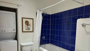 A bathroom with a white toilet, a bathtub, and a washing machine. - La Galerie Privée Luxe & Impeccable Stay (Montréal)