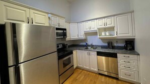 A modern kitchen with white cabinets, stainless steel appliances, and a wooden floor. - La Galerie Privée Luxe & Impeccable Stay (Montréal)