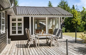 A wooden deck with a table and chairs, a covered patio area, and a view of the surrounding greenery. - Gorgeous home in Ebeltoft with WiFi (Ebeltoft)