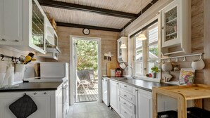 Une cuisine moderne avec des meubles blancs, un four encastré et un plafond en bois.