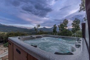 A hot tub with a stone exterior, surrounded by a stone pathway, and overlooking a mountainous landscape. - Telluride Modern Estate | Panoramic Mountain Views (Telluride)