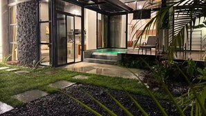 A modern house with a glass-enclosed patio, a small pool, and a well-maintained garden.