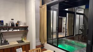 A modern kitchen with a dining area, a large sliding glass door to a pool, and a view of the pool area.