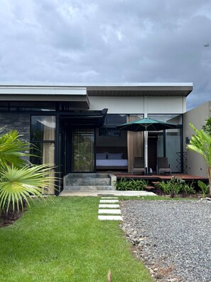 A modern house with a glass facade, a small outdoor seating area, and a well-maintained garden.