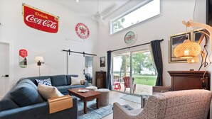 A spacious living room with a sofa, armchair, and coffee table. There is a large window providing a view of the outdoors. - New Waterfront Luxury Cabin on Lake Winnipeg (Matlock)