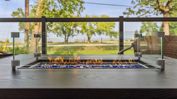 A glass-top outdoor grill with a view of a grassy area and trees. - New Waterfront Luxury Cabin on Lake Winnipeg (Matlock)