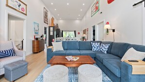A spacious living room with a blue sofa, a wooden coffee table, and a patterned armchair. - New Waterfront Luxury Cabin on Lake Winnipeg (Matlock)