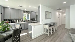 Una cocina moderna con armarios grises, una encimera blanca y una isla integrada con taburetes.