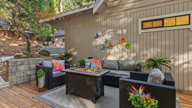 An outdoor patio with a fire pit table, wicker furniture, and decorative butterflies on the wall.