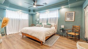 A bedroom with a wooden bed, two chairs, a small table, and a ceiling fan. - Stylish 2-bedroom Walking Distance to Downtown (Reno)