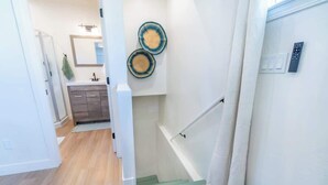 Ein modernes Badezimmer mit Dusche, Waschtisch mit Spiegel und zwei Wandkörben.
