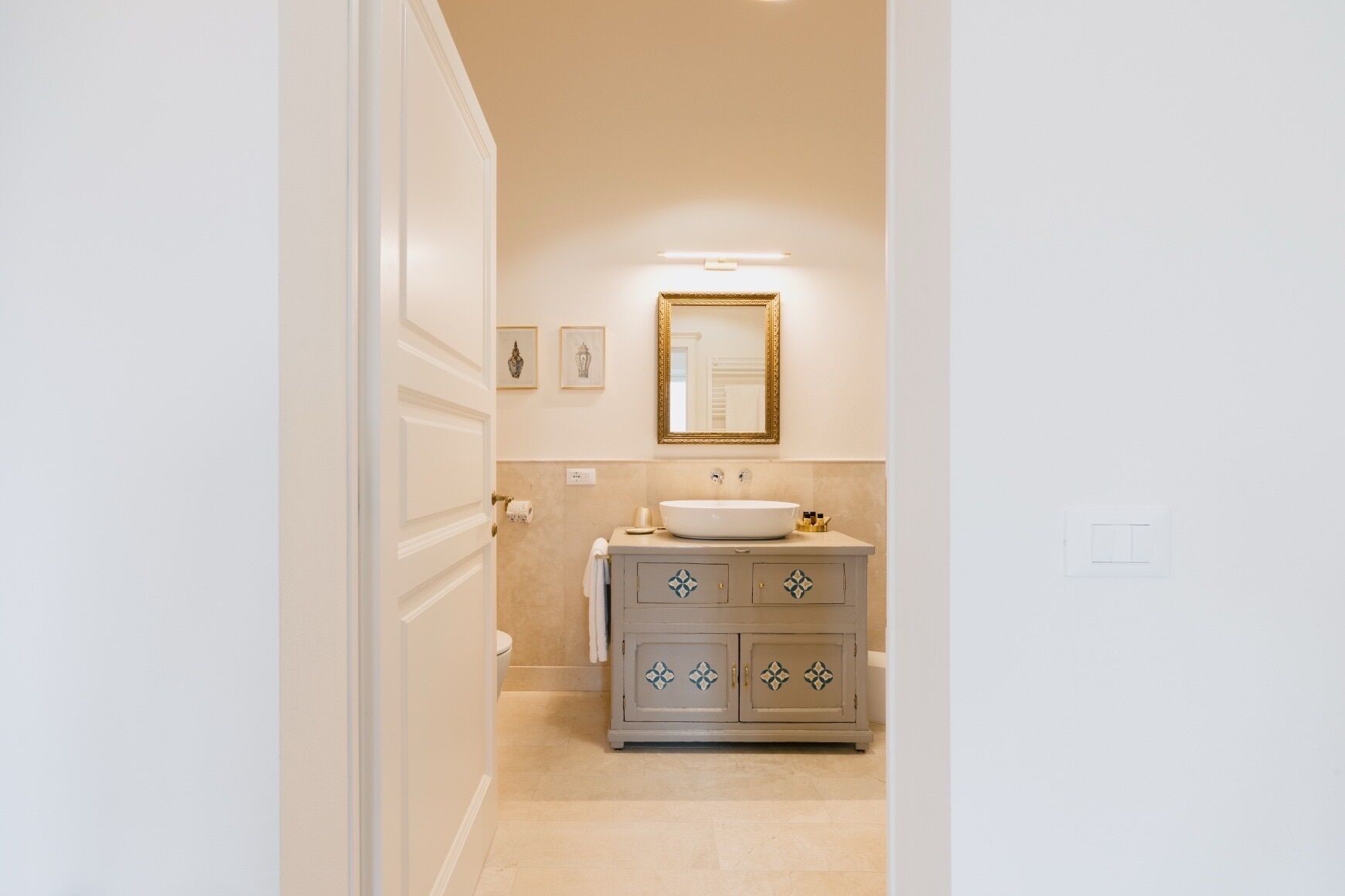 A bathroom with a white sink, a mirror, and a cabinet with decorative patterns.