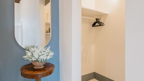A hallway with a round mirror on a wooden stand, a small table with a basket of flowers, and a tiled floor with a geometric pattern. - Premium Apartment - Helichrysum (Montepulciano)