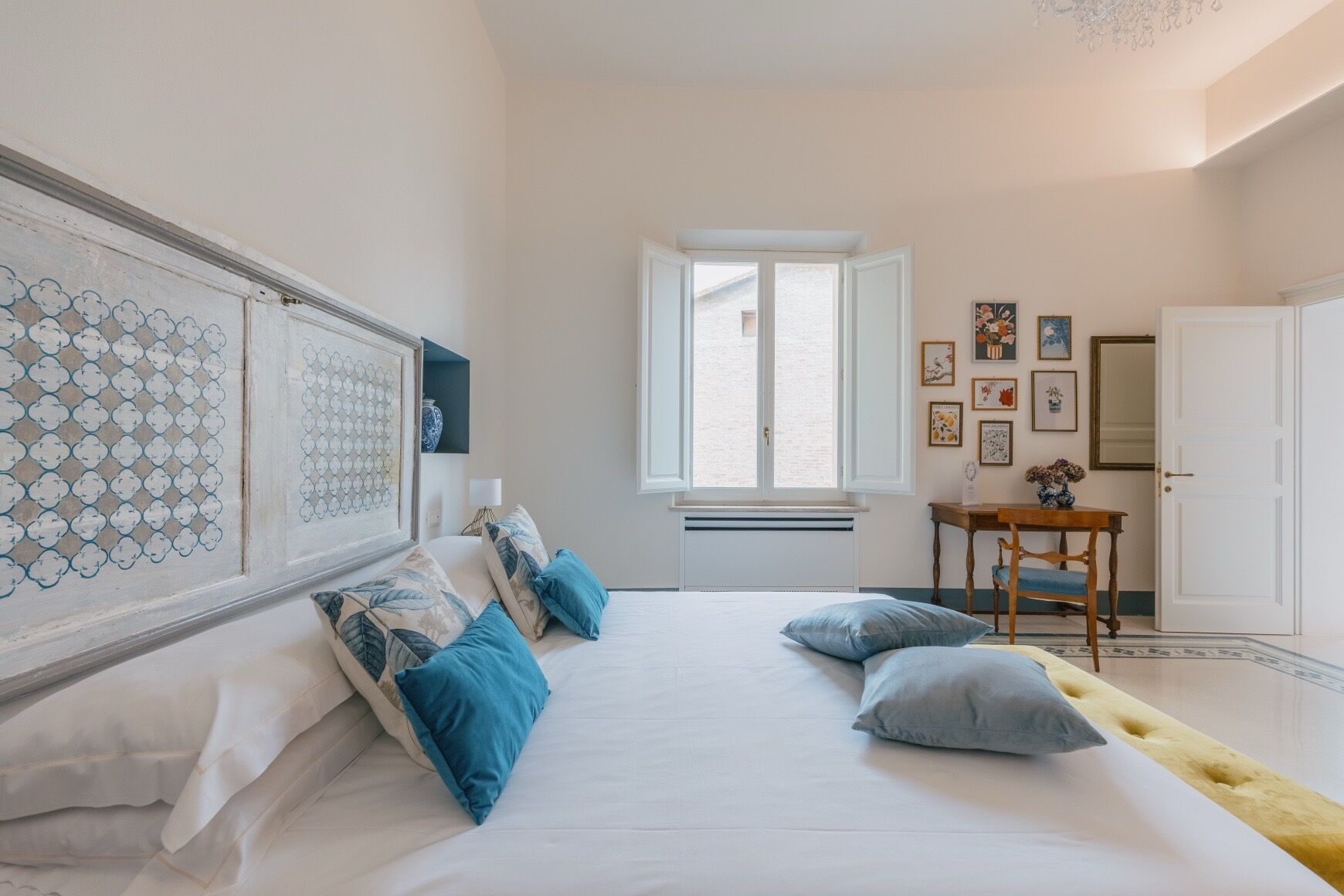Een slaapkamer met een bed, een raam, een tafel en een deur.