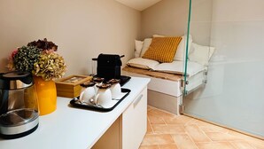 A compact living space with a kitchenette, a sofa with a patterned cushion, and a glass partition. - Quadruple Room - Dill (Montepulciano)