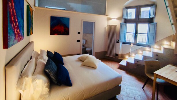 A bedroom with a bed, a window with shutters, a radiator, and artwork on the wall. - Quadruple Room - Dill (Montepulciano)