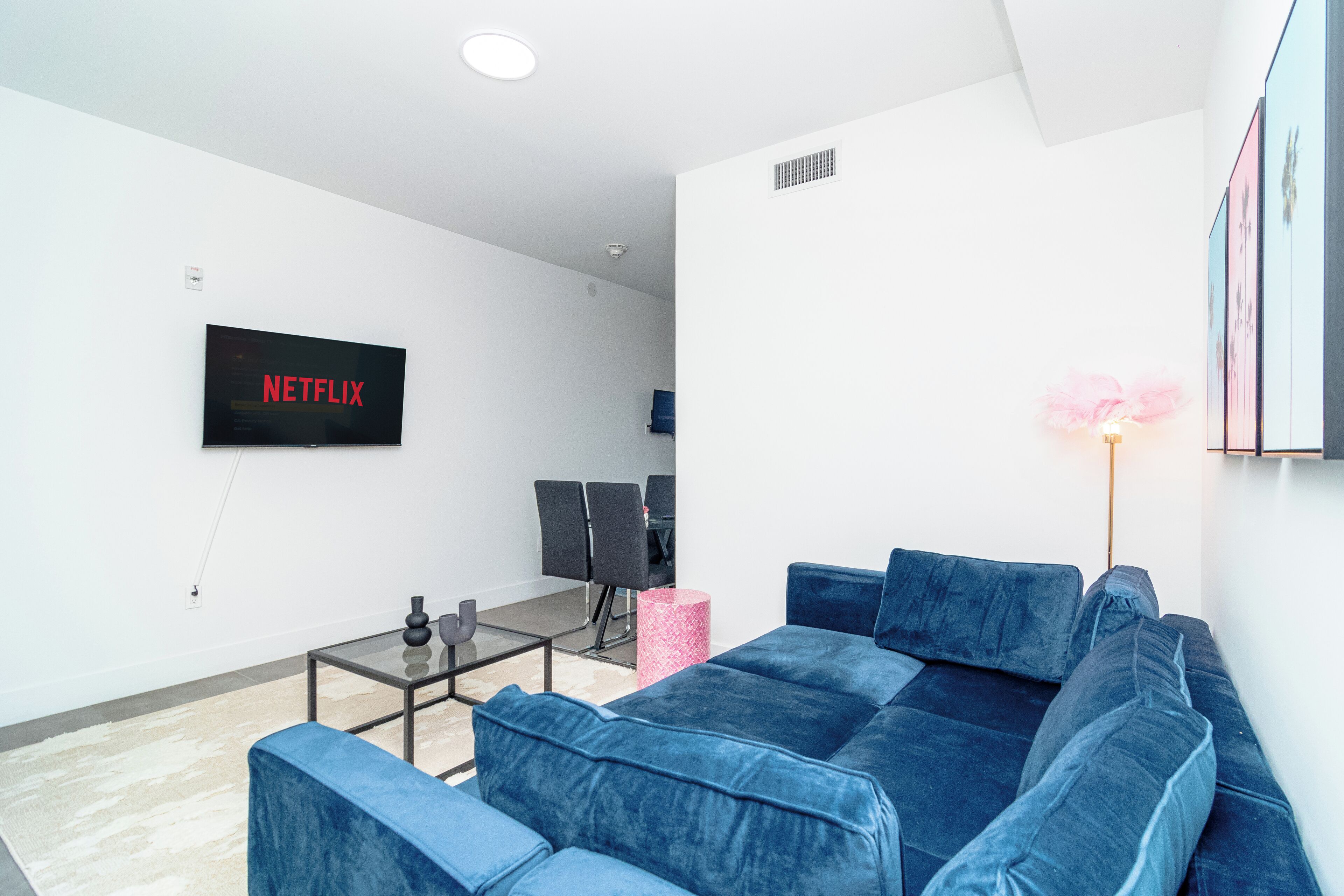 Una sala de estar moderna con un sofá azul, una mesa de centro y un televisor de pantalla plana mostrando 'NETFLIX'.