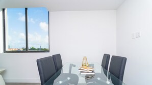 A modern meeting room with a glass table, black chairs, and a view of a cityscape through a large window. - Metro Park Hotel (Miami)