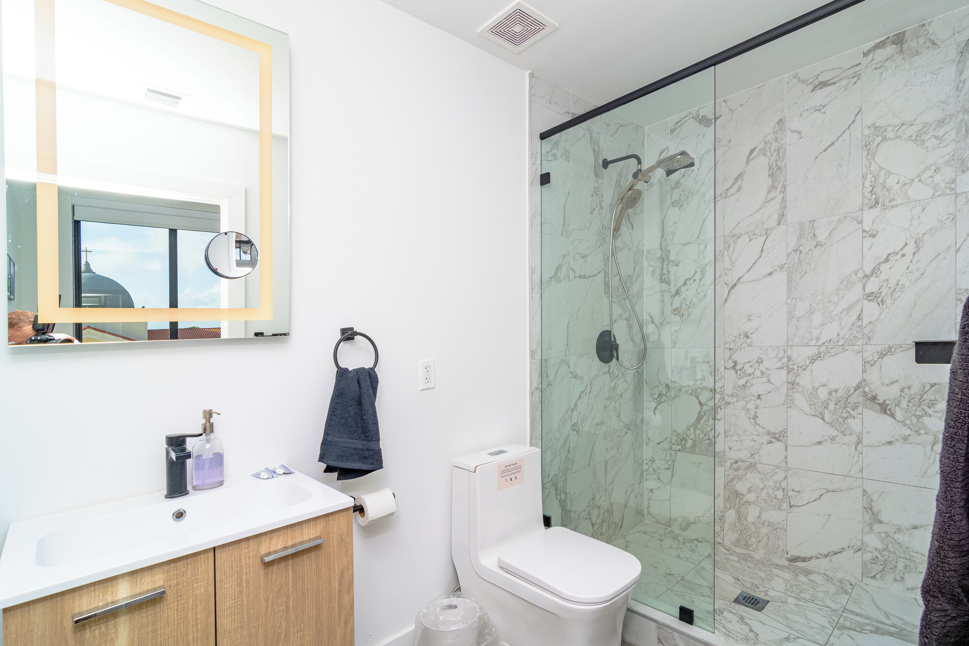Une salle de bain moderne avec une douche en marbre, un lavabo blanc et des toilettes.