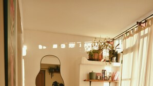 Una sala de estar acogedora con un sofá, una planta en maceta y un espejo montado en la pared.
